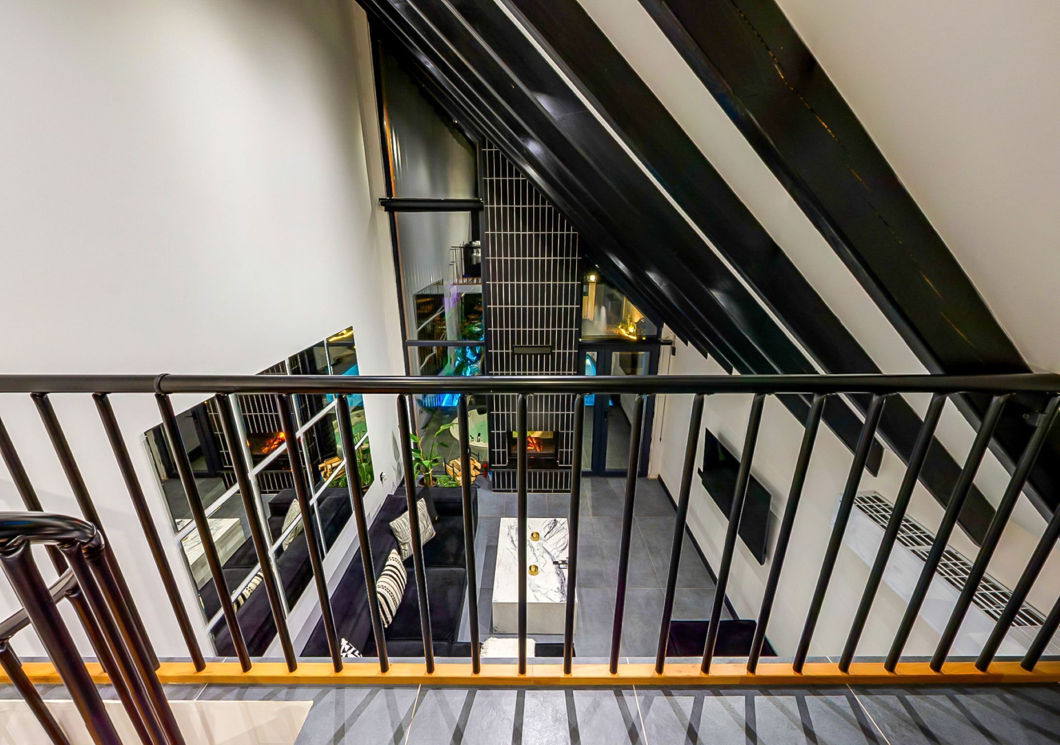 Eine Treppe mit Metallgeländer führt zu einem Wohnbereich mit einer Couch und einem Couchtisch.