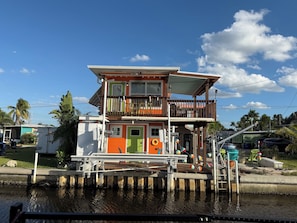 Una casa flotante de dos pisos con balcón, amarrada en un puerto deportivo.