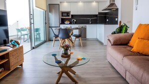 Een moderne woonkamer met een glazen salontafel, een bruine bank en een eethoek met stoelen en een tafel.
