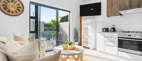 A modern kitchen with a built-in oven, a dining area with a round table, and a large window offering a view of the outdoors.