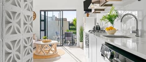 A modern kitchen with a built-in oven, a sink, and a dining area with a table and chairs.