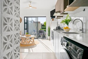 A modern kitchen with a built-in oven, a sink, and a dining area with a table and chairs. - Studio on North (Cape Town)