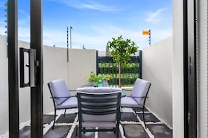 A patio with two chairs, a table, and a bottle of water. - Studio on North (Cape Town)