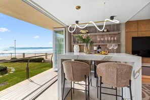 Una cucina moderna con una grande finestra vista mare, un angolo bar con sgabelli e diversi oggetti decorativi sugli scaffali.
