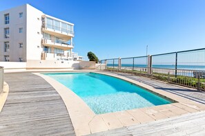 A modern building with a pool and a wooden deck.