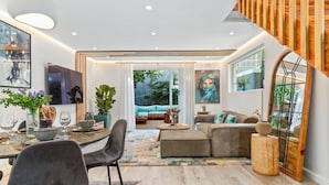 Ein modernes Wohnzimmer mit Essbereich, einer Treppe und einem großen Fenster.