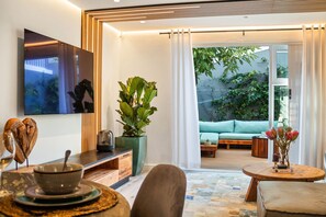 A modern living room with a sofa, coffee table, and a dining area with a table and chairs. - Selbourne Five (Cape Town)