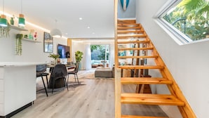 Ein modernes Interieur mit einer Holztreppe, einem Essbereich und Blick ins Freie.