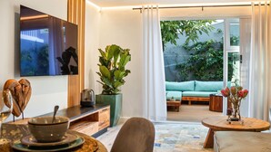 Ein modernes Wohnzimmer mit einer Couch, einem Couchtisch und einer großen Pflanze.
