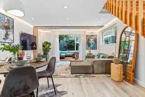 A modern living room with a dining area, a staircase, and a large window. - Selbourne Five (Cape Town)