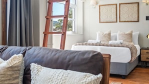Une chambre à coucher avec un lit, une échelle en bois, une fenêtre et une lampe fixée au mur.