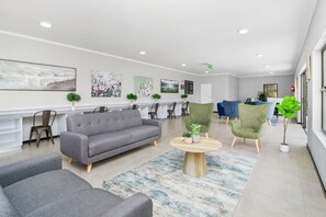 Eine moderne Lobby mit einem grauen Sofa, grünen Sessel und einem runden Holztisch.