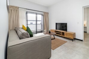 Ein modernes Wohnzimmer mit einer Couch, einem Fernseher und einer Holzkonsole.