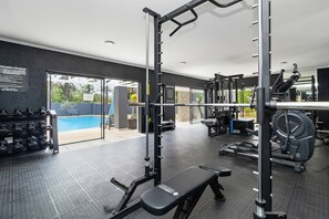 Ein Fitnessraum mit Klimmzugstange, Gewichtshebelbank und Kurzhanteln.