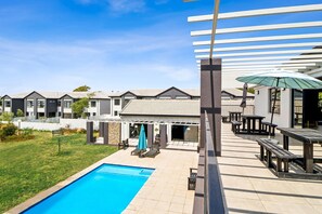 Ein Wohnkomplex mit Schwimmbad, Außenbereich zum Sitzen und einer überdachten Terrasse.