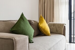Ein Sofa mit zwei Kissen, ein Fenster mit Vorhängen und Blick ins Freie.