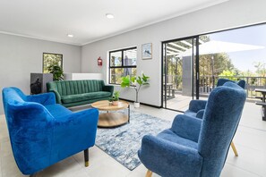 Ein modernes Wohnzimmer mit einem grünen Sofa, blauen Sesseln und einem Couchtisch.