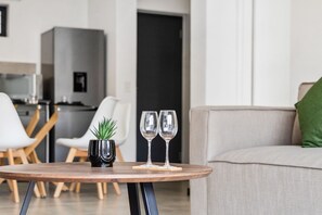 A modern living room with a round wooden table, two wine glasses, and a small potted plant. - Mandalay Hideaway (Johannesburg)