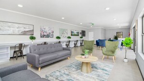 A modern lobby with a grey sofa, green armchairs, and a round wooden coffee table. - Mandalay Hideaway (Johannesburg)