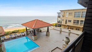 A rooftop pool with a view of the ocean, a covered seating area, and a building with multiple windows. - Bali Hai 103 (Westbrook)