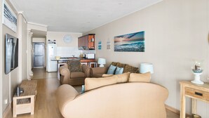 A modern living room with a large sofa, a dining area, and a kitchen in the background. - Bali Hai 103 (Westbrook)