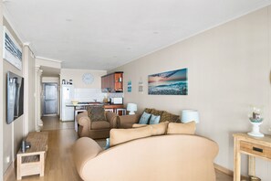 Una sala moderna con un sofá grande, un comedor y una cocina al fondo.