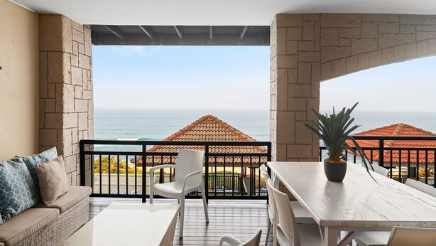 A balcony with a view of the ocean, a dining table, a sofa, and a potted plant. - Bali Hai 103 (Westbrook)