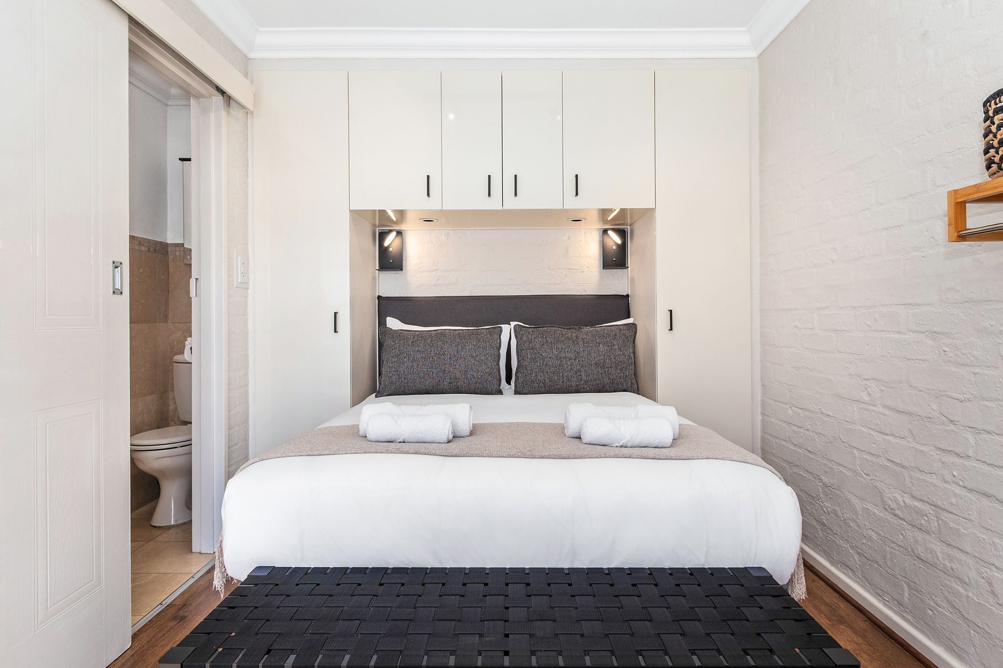 A bedroom with a bed, a wardrobe, and a bathroom visible through an open door.