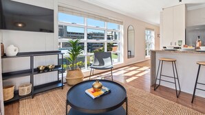 A modern kitchen with a large window, a black round table, and bar stools. - Harbour Terrace 7 (Cape Town)