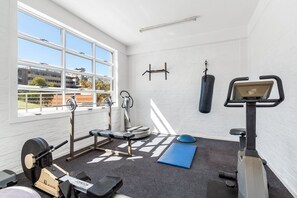 A gym with a rowing machine, bench press, and a punching bag.