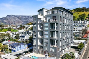 Un hotel de varios pisos con balcones, una piscina y vistas a un paisaje montañoso.