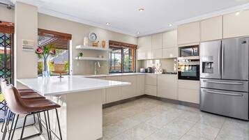A modern kitchen with a central island, stainless steel appliances, and a bar area with stools.