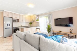 Un appartement moderne doté d’une kitchenette, d’un canapé, d’un coin repas et d’une télévision.
