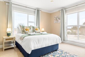 Une chambre avec un grand lit, deux tables de chevet, une fenêtre et une vue.