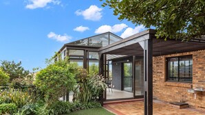 Ein modernes Haus mit Wintergarten, Backsteinfassade und einem gepflegten Garten.