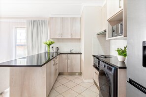 Une cuisine moderne équipée d’un lave-linge encastré, d’un évier et d’un plan de travail.