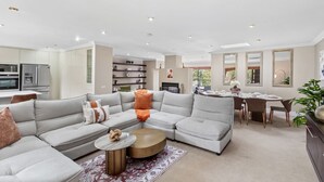 Ein modernes Wohnzimmer mit einer Eckcouch, einem runden Couchtisch und einem Essbereich mit Tisch und Stühlen.