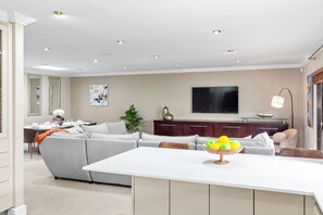 A modern living room with a sofa, dining table, and a TV. - Warwick Coastal Harmony (Cape Town)