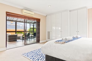 Una habitación de hotel con cama, un ventanal que da a una zona de estar exterior y un armario.
