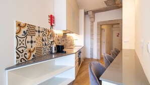 A modern kitchen with patterned tiles, a stainless steel kettle, and a built-in oven. - Caldeireiros 95 | Charming Home (Porto)