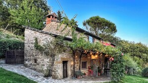 A stone house with a stone pathway leading to a wooden door, surrounded by greenery and a clear sky. - La Fonte - Two Bedroom House, Sleeps 4 (Subbiano)