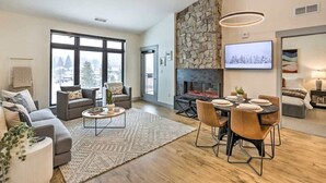 Una sala de estar moderna con chimenea, un comedor y un amplio ventanal con vista a la ciudad.