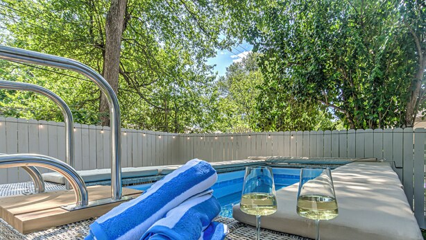 Un patio trasero con piscina, sillas de descanso y una terraza de madera.