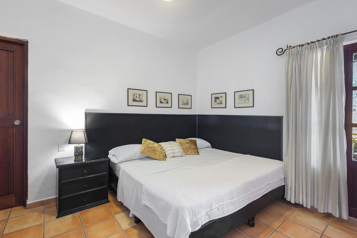 Een slaapkamer met een bed, nachtkastje en een deur.