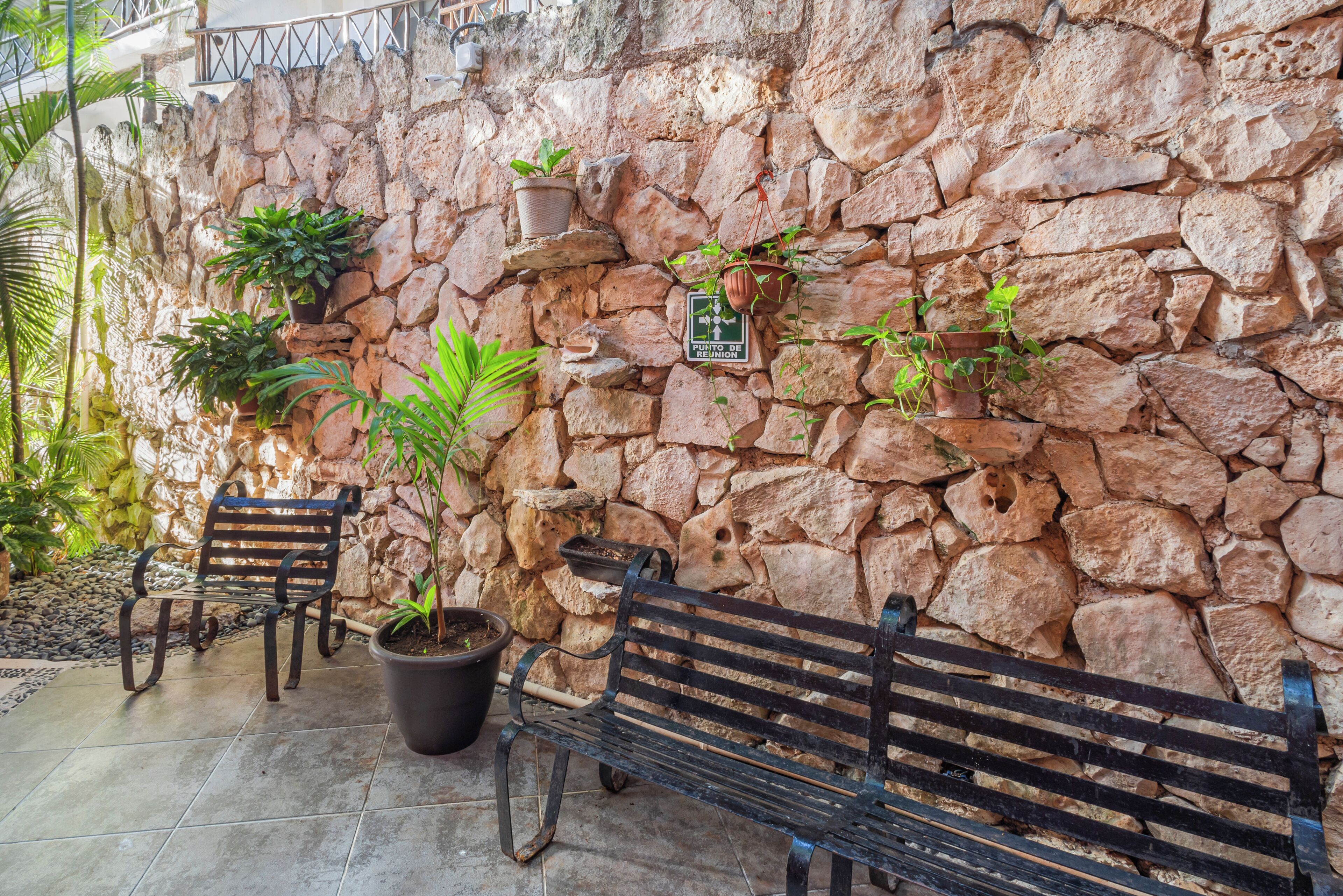 A stone wall with potted plants and a bench.
