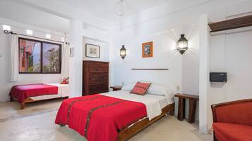 Une chambre avec deux lits, une armoire en bois, une table de chevet, un banc et un luminaire fixé au mur.
