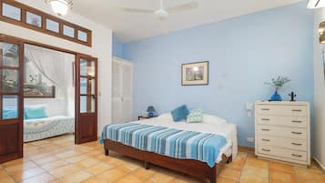 A bedroom with a bed, a dresser, a ceiling fan, and a window with curtains.