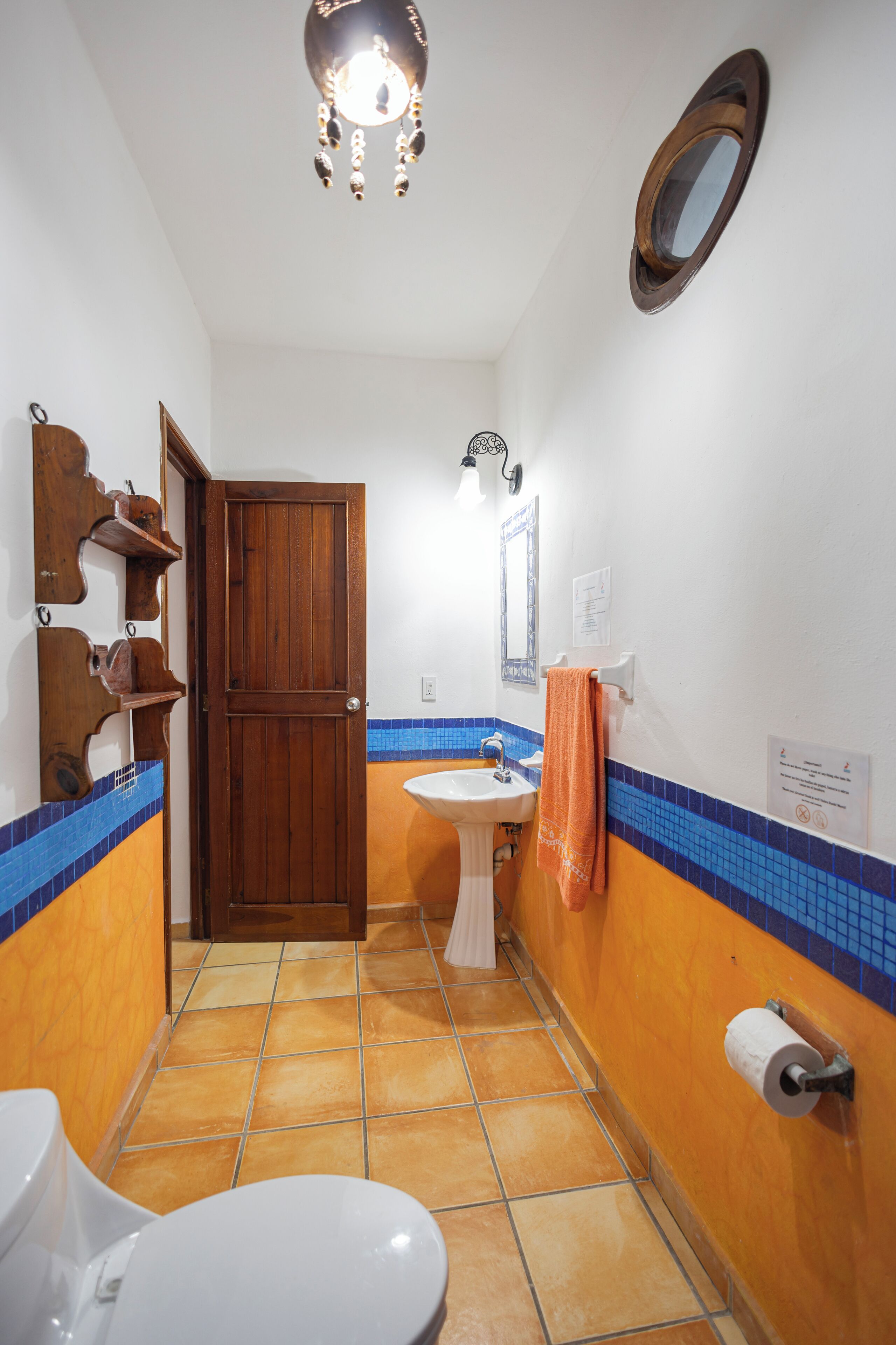 A bathroom with a wooden door, a white sink, and a blue-tiled floor.