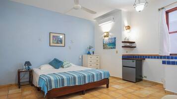 A bedroom with a bed, nightstand, dresser, and a small refrigerator.