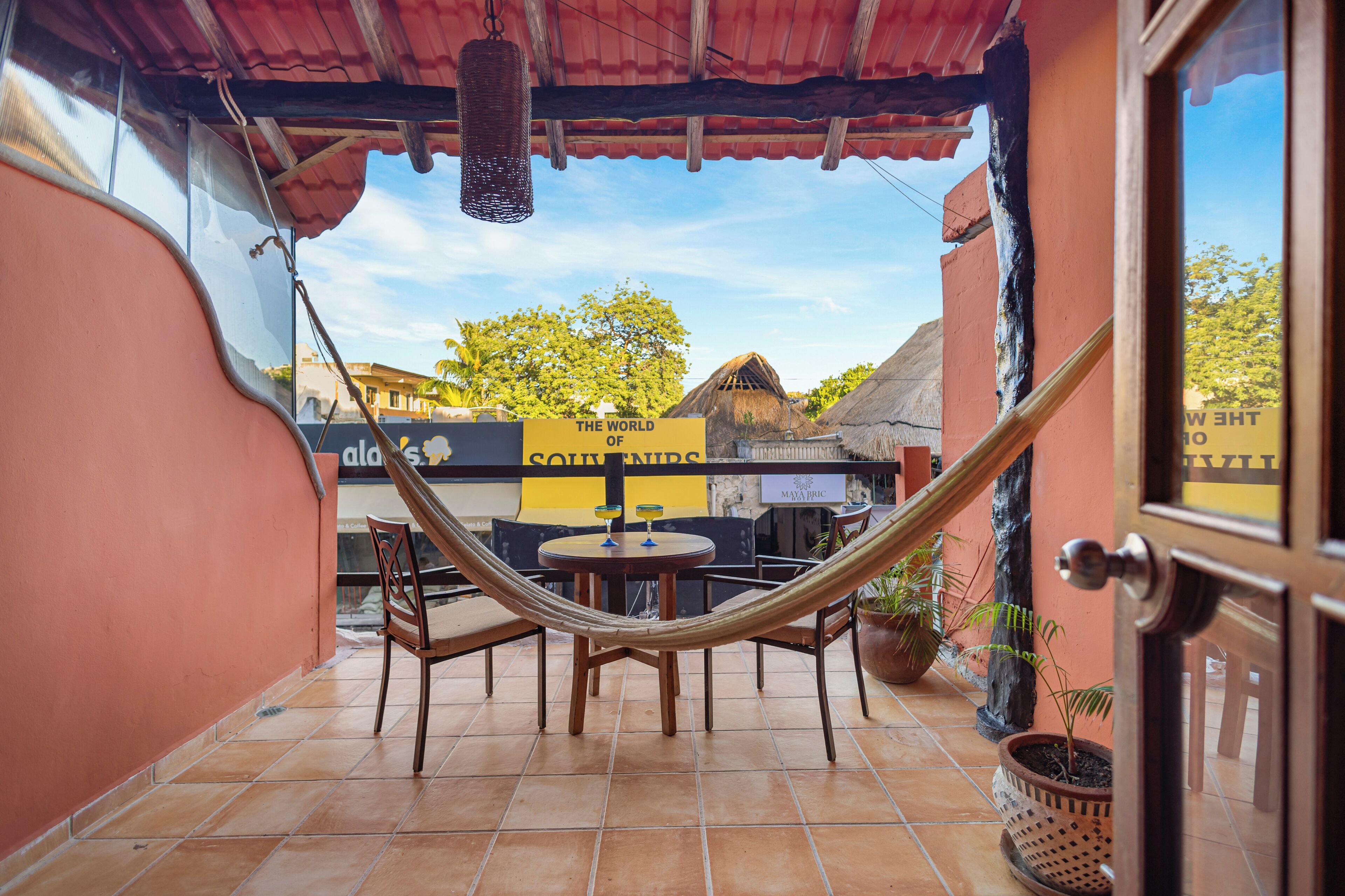 A hammock chair and table set up on a tiled patio with a view of a building labeled "The World of Souvenirs."